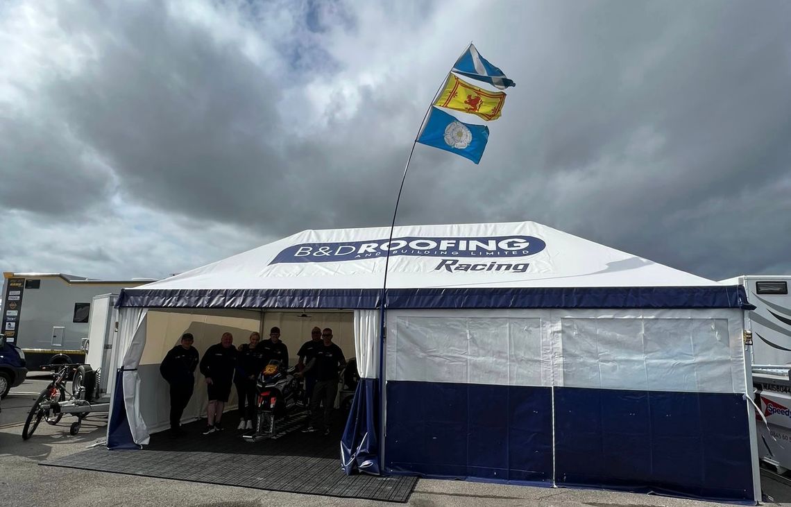 A large race awning with people in the doorway. A flag is attached to it.