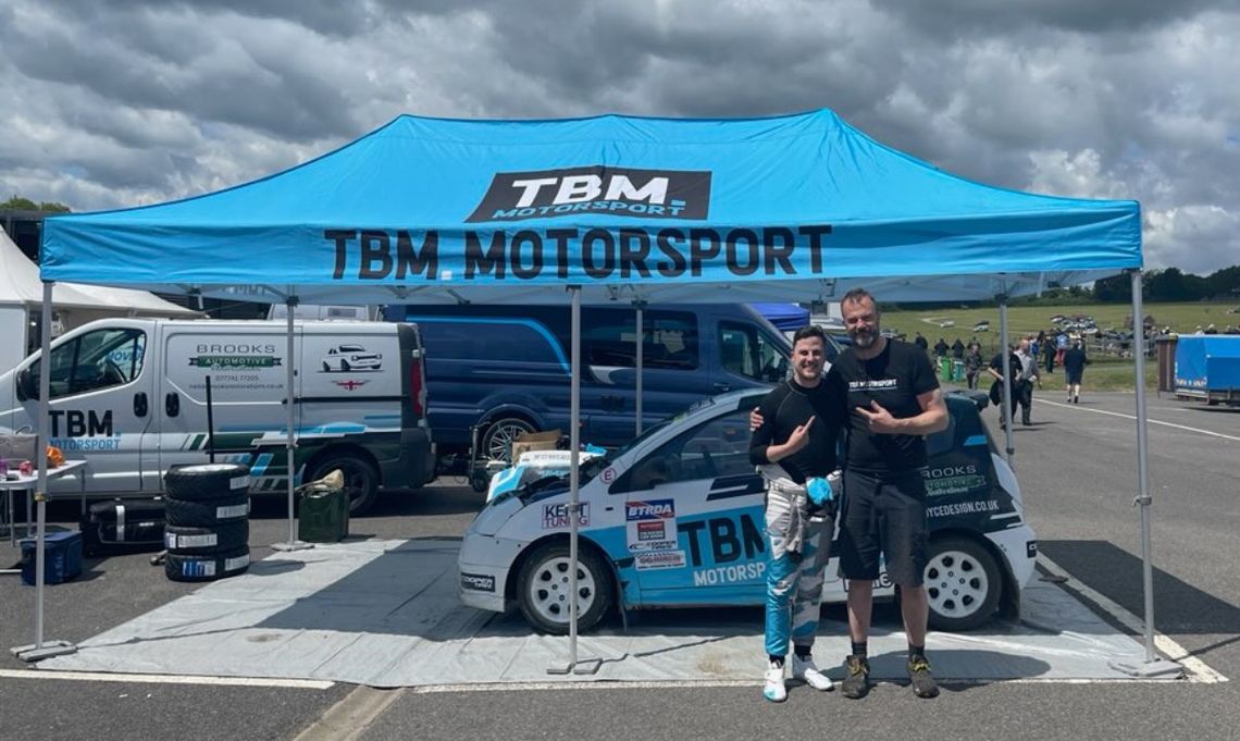 A printed 3m x 6m pop up race tent with two men in front of it with a vehicle beneath the canopy