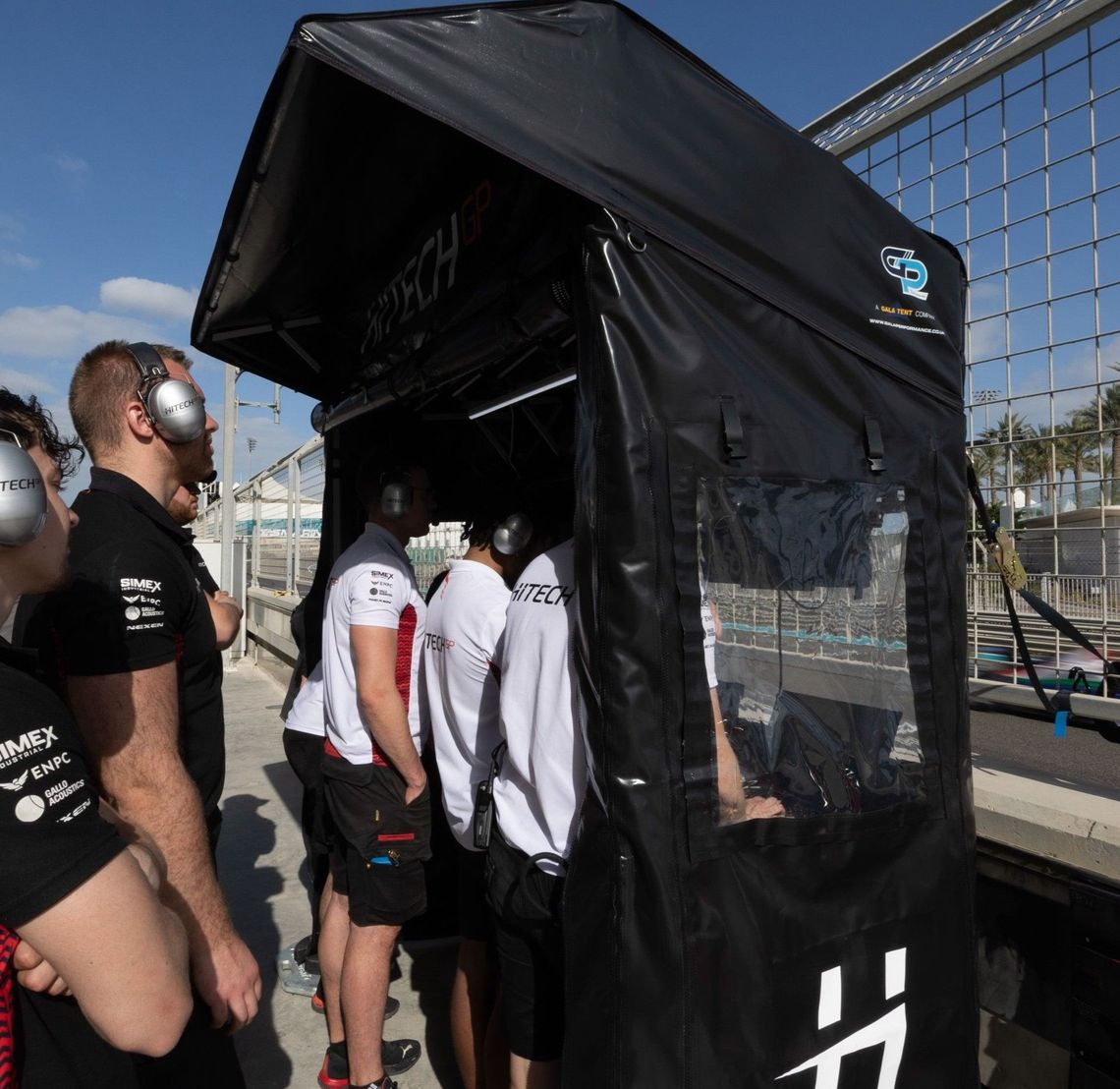 a motorsport crew beneath a pit perch